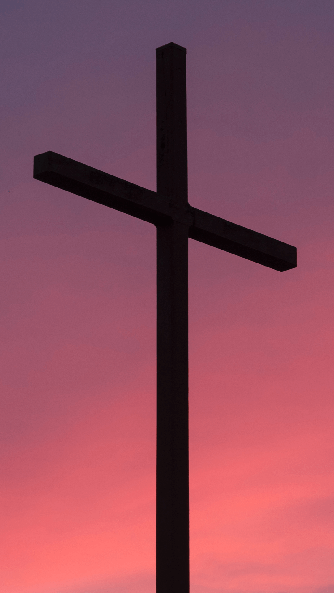 Silhouette eines einfachen Kreuzes vor einem rosa-lila Sonnenuntergang.